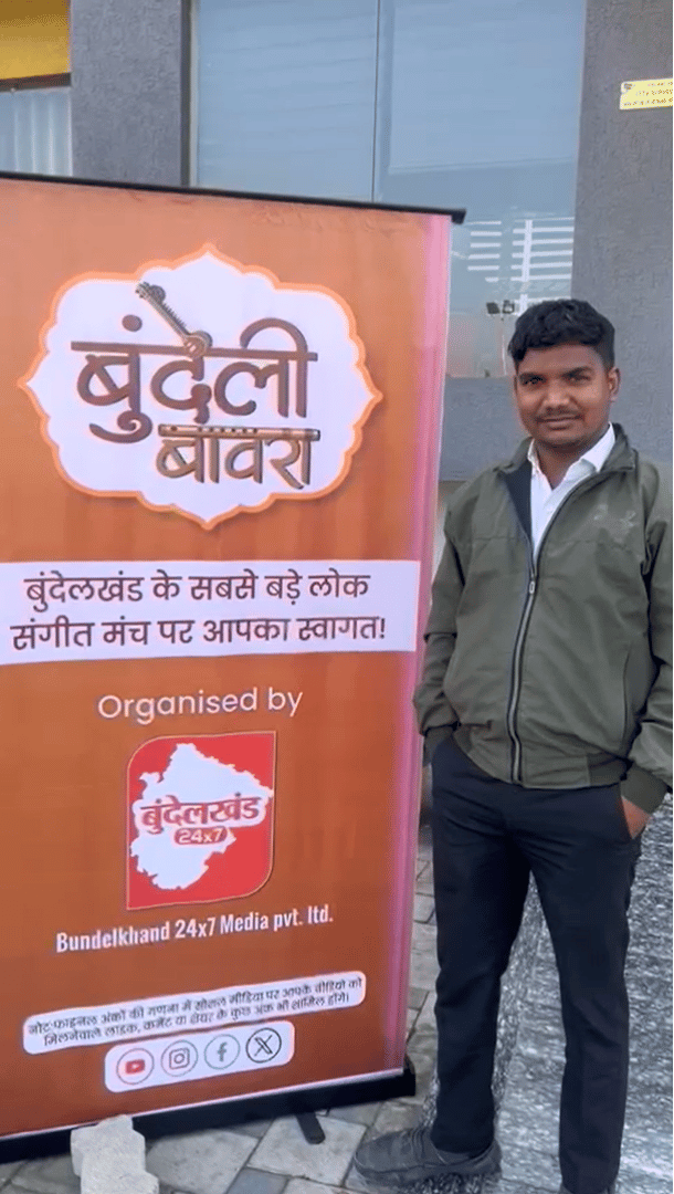 Participant posing near the Bundeli Bawra event banner